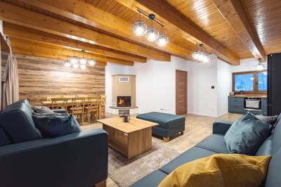 Obývačka s rozkladacím gaučom a jedálenským sedením pri krbe, Chalety Bučina, Oravská Lesná