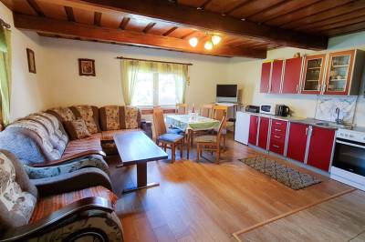 Obývačka s rozkladacím gaučom a  TV prepojená s kuchyňou s jedálenským sedením, Chata Oravka, Pokryváč